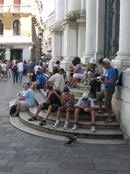 Turisti che mangiano sui gradini di una chiesa a Venezia